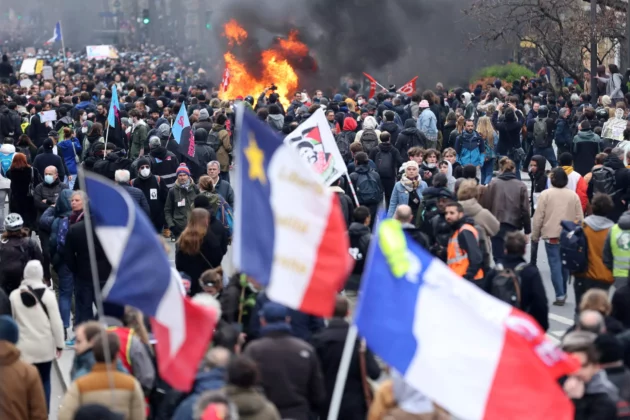 抗議者は、2023年3月28日、フランスのパリでフランス政府の年金改革に対する全国的なストライキと抗議の10日目の一環として、デモでの衝突中に火の近くにフランス国旗を掲げています。ロイター/Nacho Doce REUTERS - NACHO DOCE