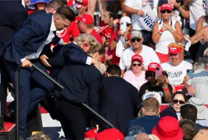 共和党候補のドナルド・トランプは、シークレットサービスエージェントに囲まれて顔に血がついているのが見られる © Rebecca DROKE / AFP