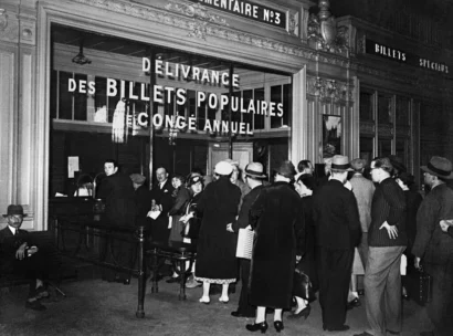 人々は1936年の夏に行楽客のために割引価格の列車のチケットを買うためにフランスの駅に並んでいます。© AFP