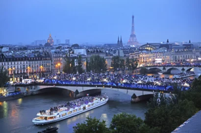 観客は、2024年7月26日金曜日にフランスのパリで開催された2024年夏季オリンピックの開会式で、チームフランスのアスリートがセーヌ川をクルーズするのを見ています。AP - リチャード・ヒースコート
