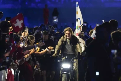 トム・クルーズは、2024年8月11日(日)にフランスのサン=ドニで開催されたスタッド・ド・フランスで開催された2024年夏季オリンピックの閉会式で、オリンピック旗を掲げたバイクに乗る。AP - アシュリー・ランディス